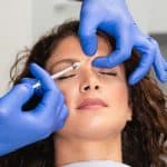 experts hands injecting botox in female forehead min